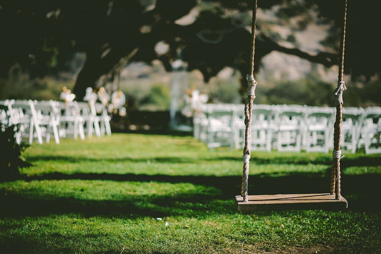 Wooden swing on a lawn set with chairs for a wedding