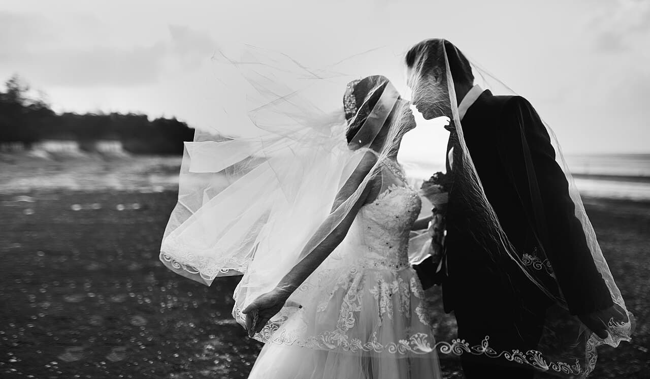 Couple on a windy beach, veil blowing