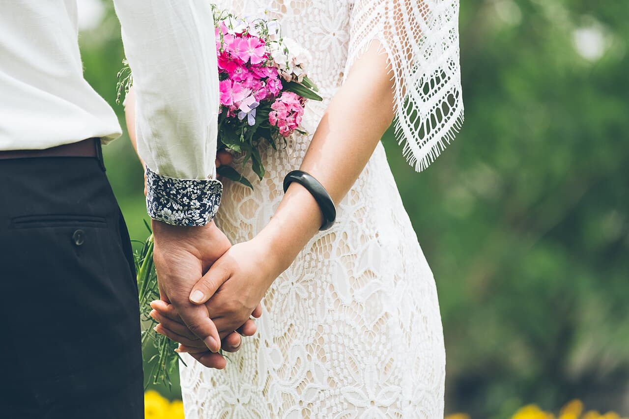 Bride and groom holding hands with a bouquet