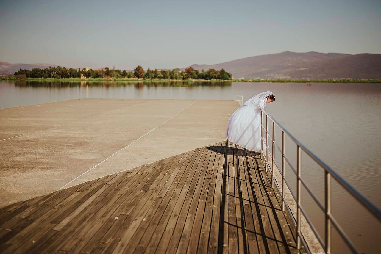 Bride standing on a wooden dock by a lake